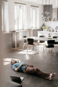 Man lying on the floor next to laptop