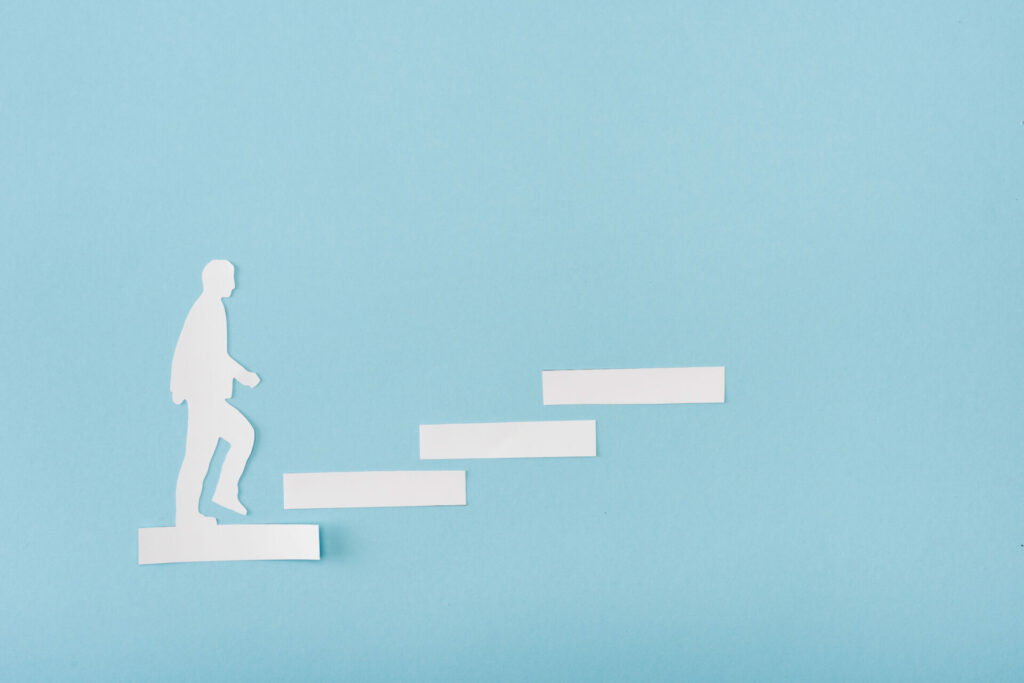 top-view-of-paper-man-on-career-ladder-on-blue